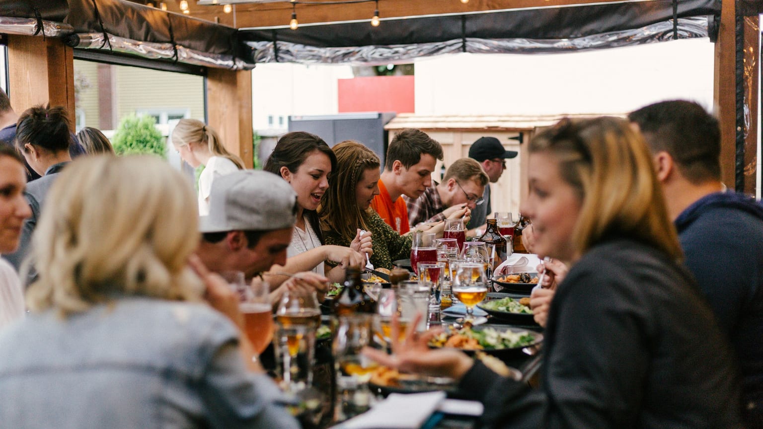 Friends gathered around a long outdoor table sharing a meal
