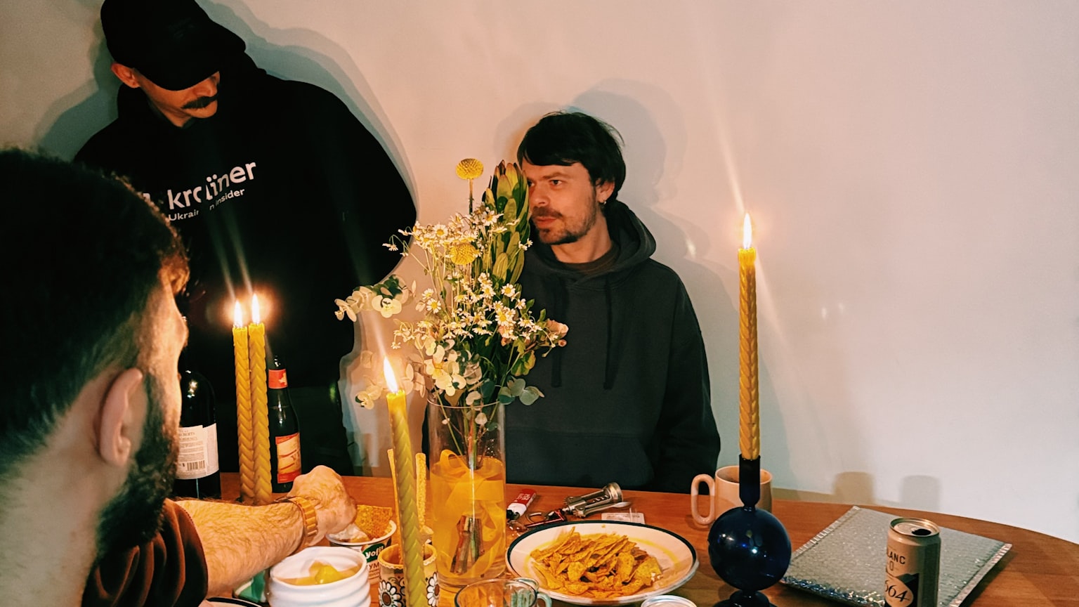 Friends gathered around a candlelit table with food and drinks during a casual evening together