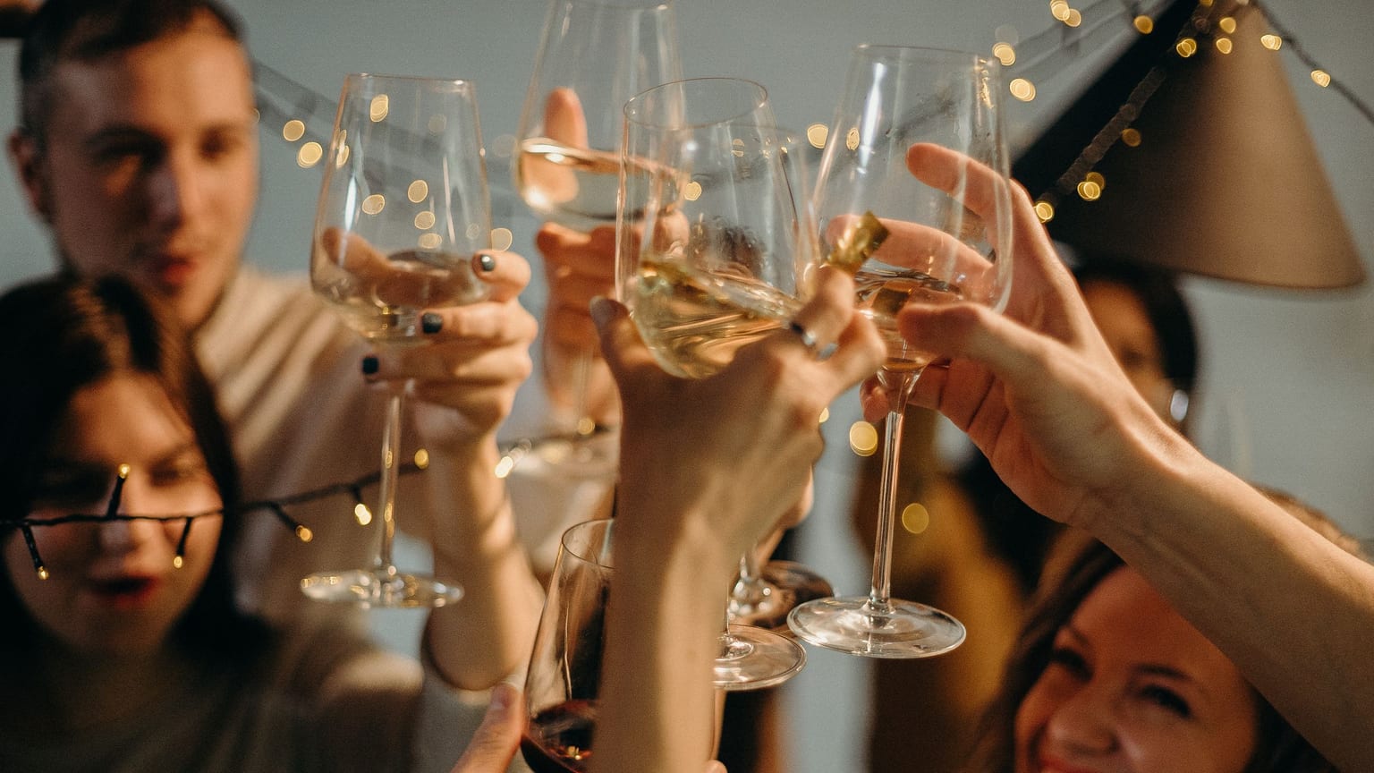 Friends raising glasses together in a warm indoor celebration